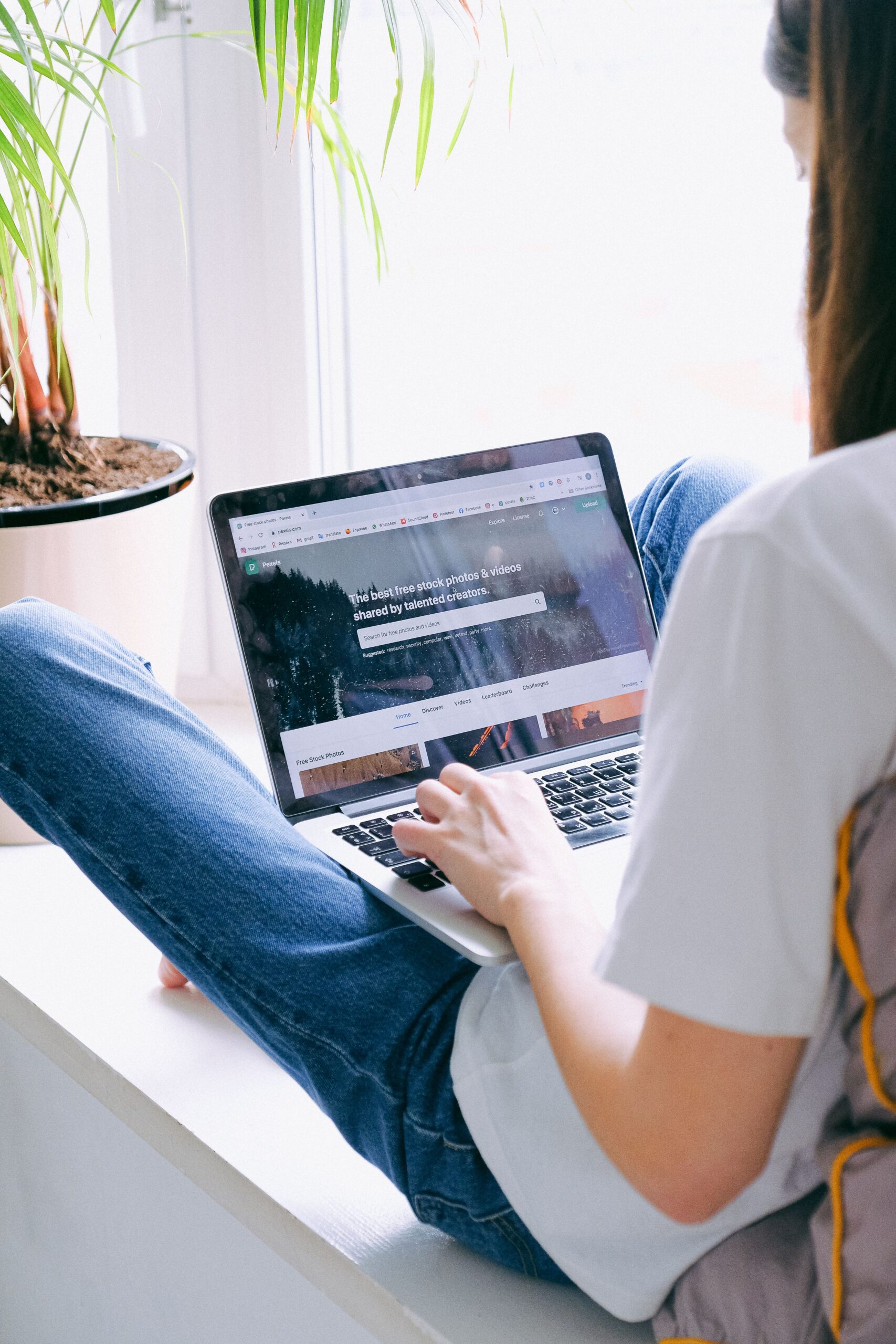 Young woman comfortably working on a laptop indoors, symbolizing remote work lifestyle.